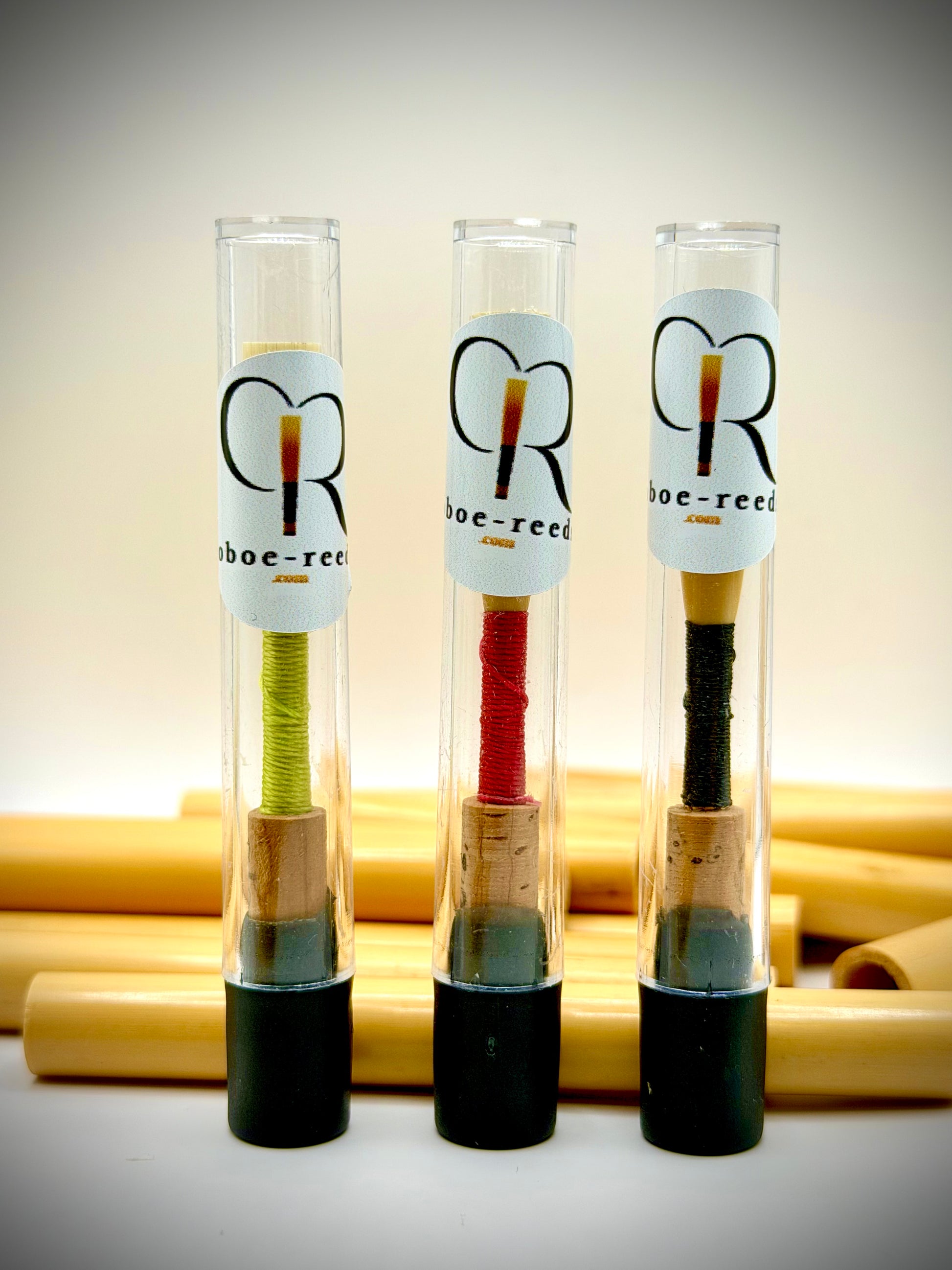 Three handmade oboe reeds in protective tubes with natural oboe cane