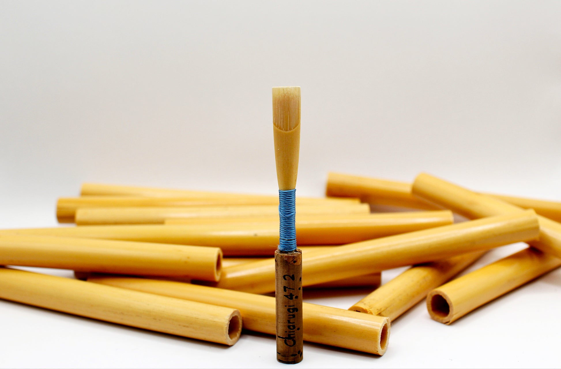 Handmade student oboe reed surrounded by selected oboe cane